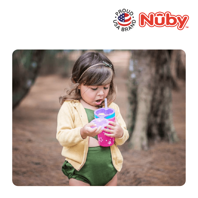 Astra Family A little girl drinking from a cup in the woods.