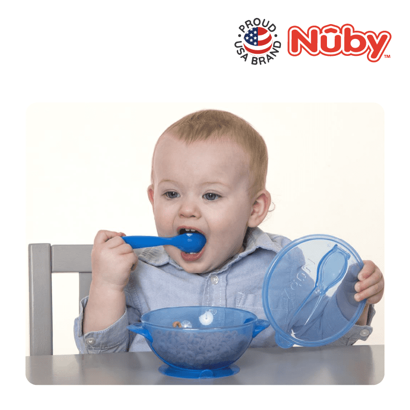 Astra Family A baby is eating with a blue bowl and spoon.