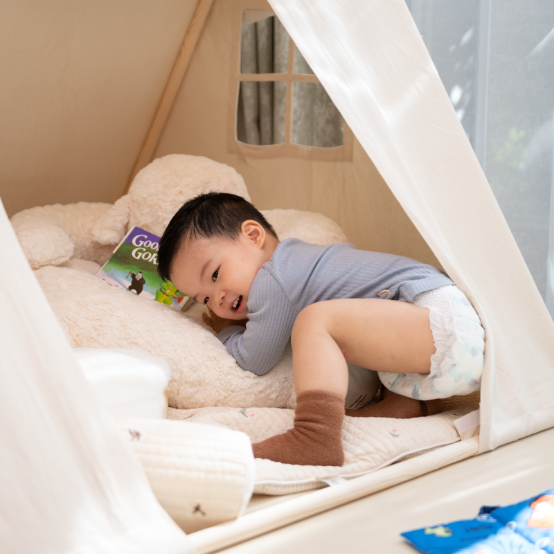 Astra Family A newborn baby laying in a teepee wearing Hoppi New Born Diapers -66 pcs with an umbilical cord hole.