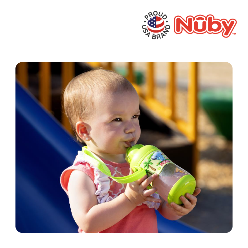 Astra Family A baby is holding a Nuby Tritan Flip It kindergarden water bottle in front of a slide.