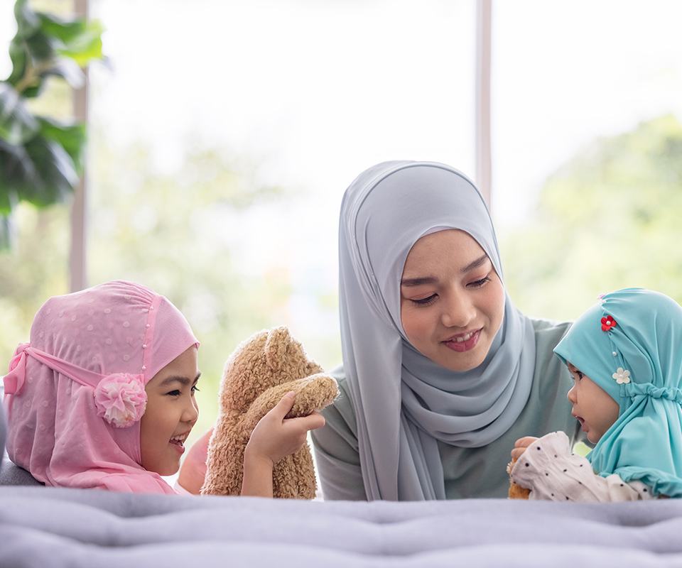 Astra Family A woman in hijab is playfully interacting with her children at home.
