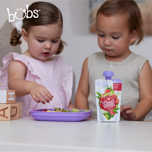 Astra Family Two little girls playing with Bubs® Organic Strawberry, Pear and Quinoa, a healthy organic baby food pouch.
