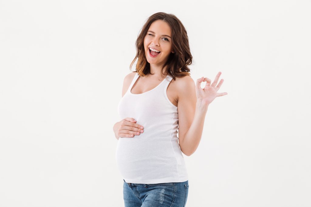 Astra Family Pregnant woman confidently showing ok sign, preparing for motherhood.
