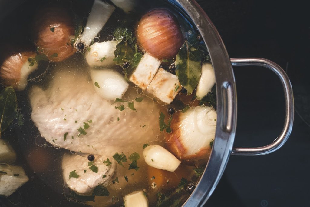 Astra Family A pot of bone broth chicken soup with onions and carrots, packed with the benefits of bone broth for your baby.