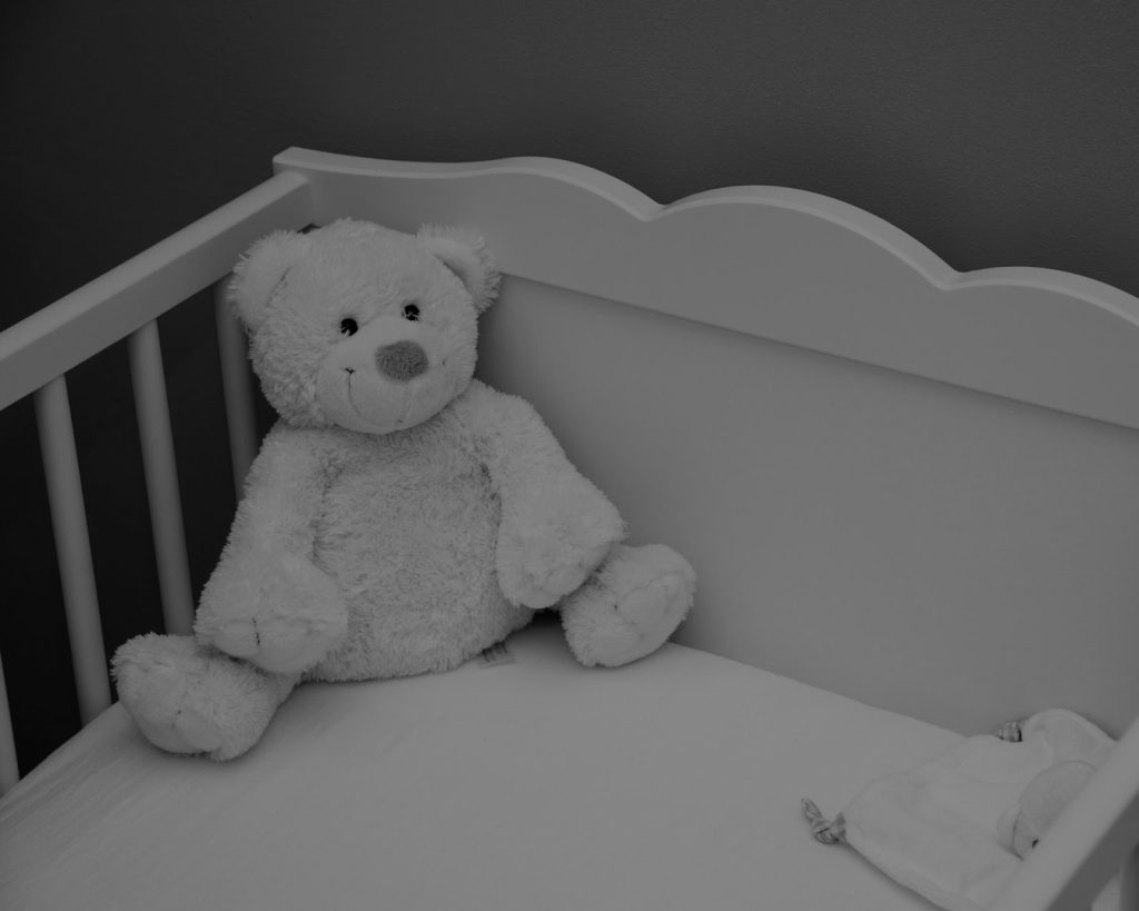 Astra Family A teddy bear providing comfort in a crib after experiencing pregnancy loss.